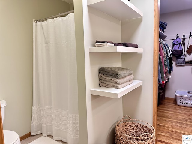 bathroom featuring toilet, baseboards, and wood finished floors