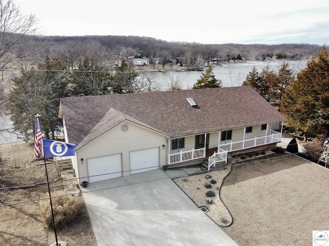 view of front facade featuring roof with shingles, covered porch, an attached garage, fence, and driveway