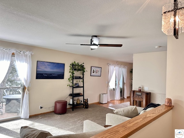 living room featuring ceiling fan, a textured ceiling, and baseboards