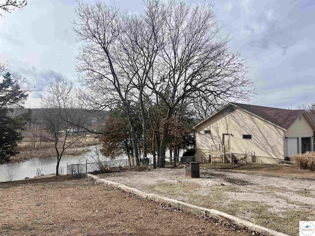view of home's exterior with a water view and fence