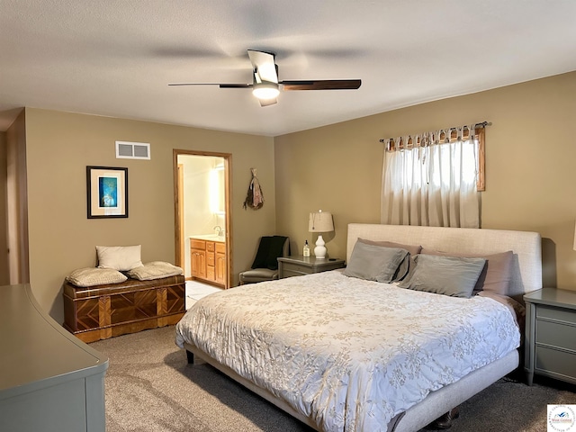 bedroom featuring a ceiling fan, visible vents, light carpet, and ensuite bath