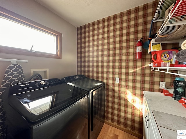 washroom with light wood-type flooring, laundry area, wallpapered walls, and washer and dryer