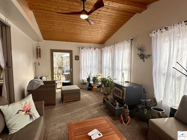 interior space with wood ceiling, a wood stove, a healthy amount of sunlight, and vaulted ceiling with beams