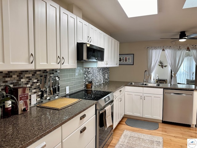 kitchen with appliances with stainless steel finishes, dark stone counters, white cabinets, and a sink