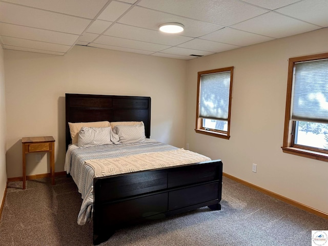 bedroom with dark colored carpet, a drop ceiling, visible vents, and baseboards