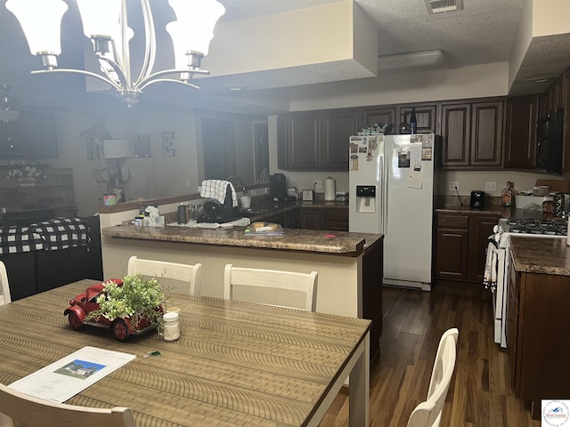 kitchen featuring black microwave, white refrigerator with ice dispenser, dark wood finished floors, gas range, and an inviting chandelier