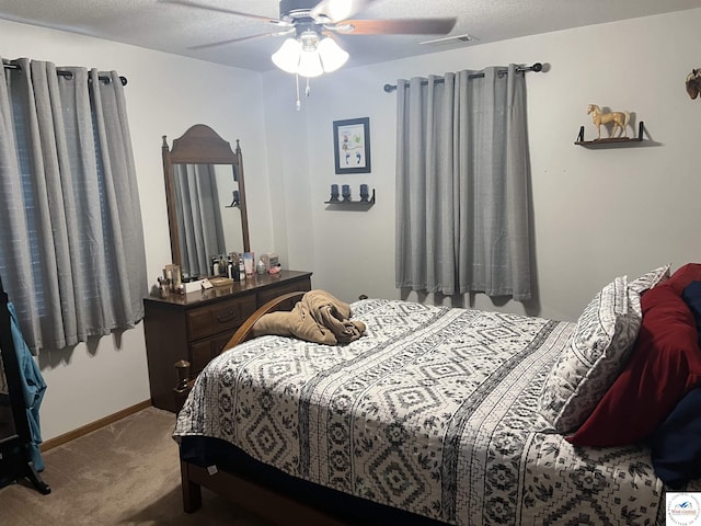 carpeted bedroom with a ceiling fan, visible vents, baseboards, and a textured ceiling