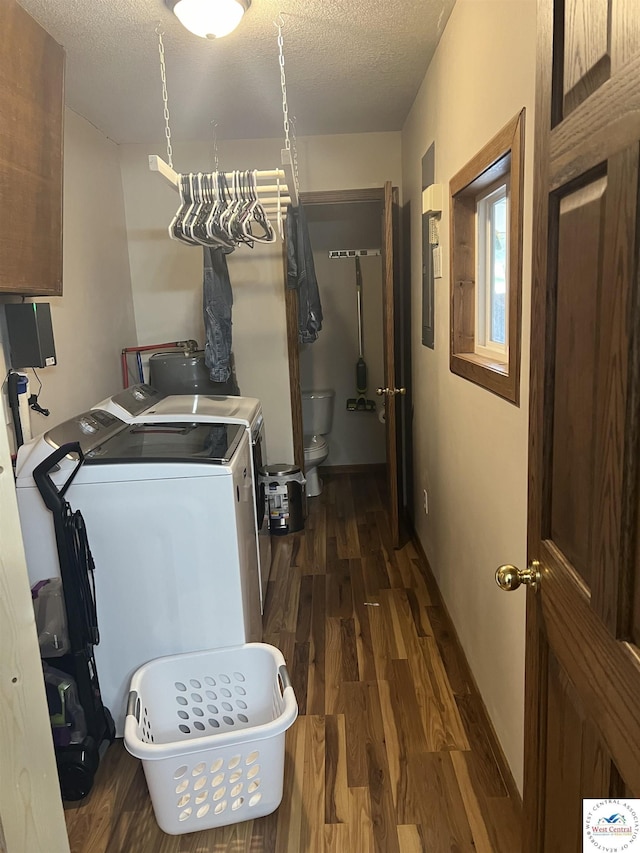 clothes washing area with a textured ceiling, separate washer and dryer, dark wood-style flooring, and baseboards