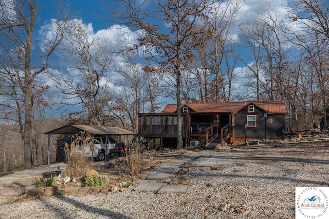 view of front of house with a detached carport, driveway, and metal roof