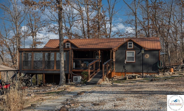 chalet / cabin featuring metal roof, a sunroom, and stairway