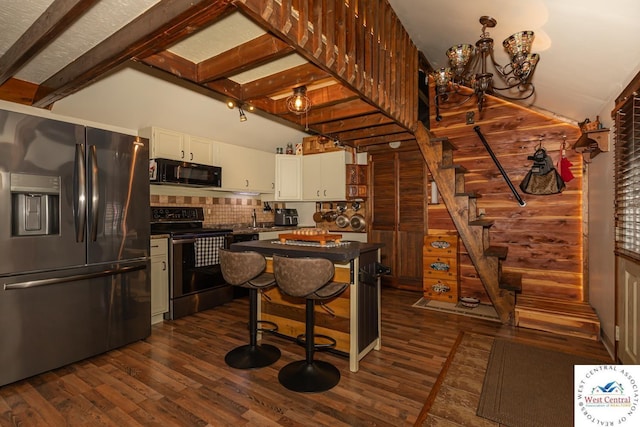 kitchen with dark countertops, dark wood-style floors, white cabinetry, appliances with stainless steel finishes, and vaulted ceiling with beams