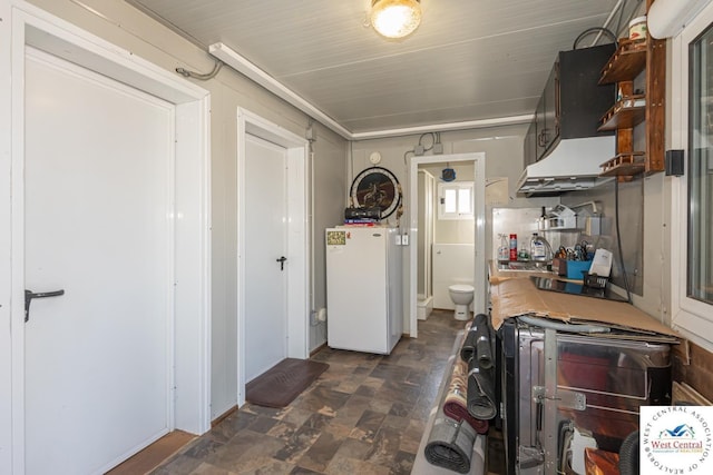 interior space with stone finish floor, freestanding refrigerator, and a sink