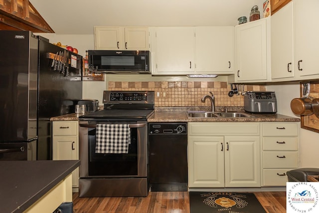 kitchen featuring black appliances, dark countertops, and a sink