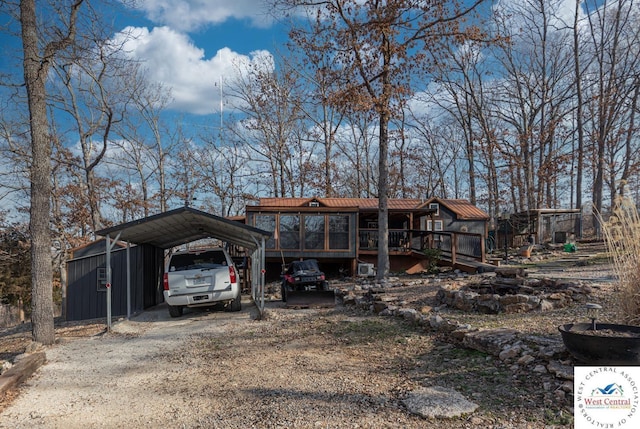 view of front of home featuring a carport, dirt driveway, and a wooden deck