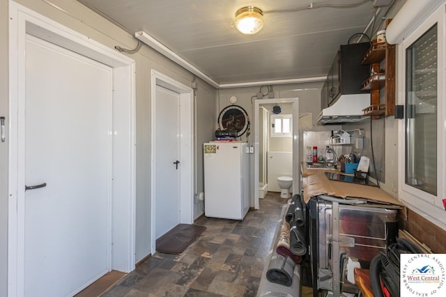 kitchen with open shelves, exhaust hood, light countertops, and freestanding refrigerator