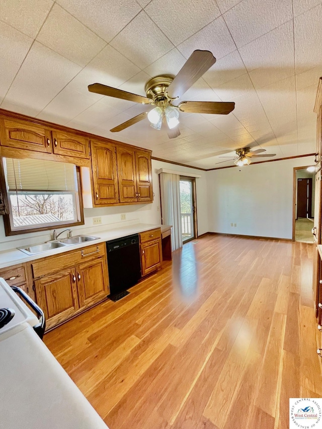 kitchen featuring black dishwasher, brown cabinets, light countertops, a sink, and light wood-type flooring