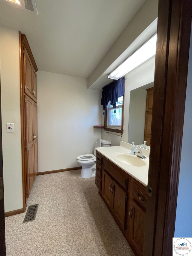 bathroom with toilet, vanity, visible vents, and baseboards