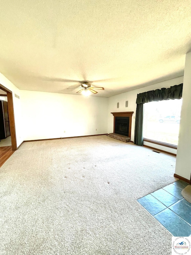 unfurnished living room with a fireplace with raised hearth, ceiling fan, a baseboard radiator, a textured ceiling, and carpet floors