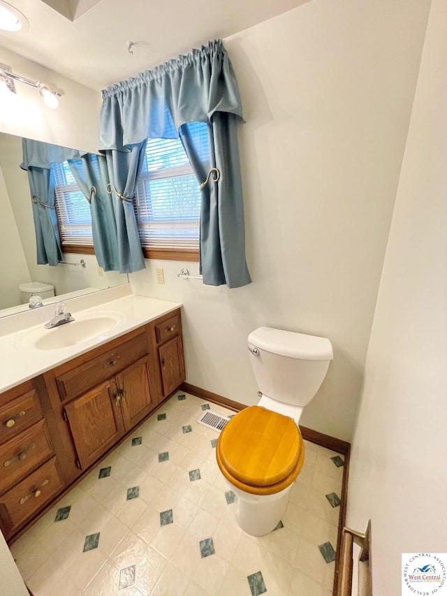 bathroom featuring visible vents, vanity, toilet, and baseboards