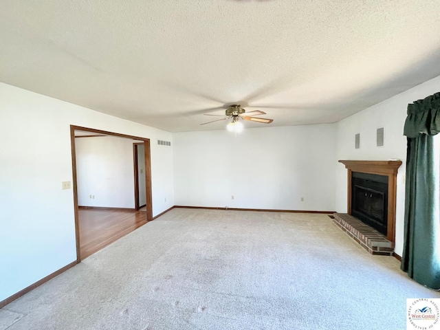 unfurnished living room with visible vents, ceiling fan, carpet, a textured ceiling, and a brick fireplace