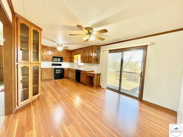 kitchen featuring light wood-style floors, glass insert cabinets, brown cabinets, light countertops, and black appliances