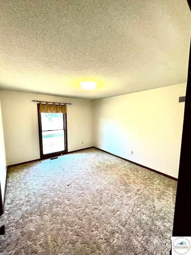 carpeted empty room with baseboards, visible vents, and a textured ceiling