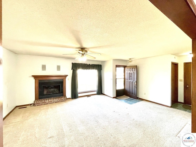 unfurnished living room with carpet, a fireplace, visible vents, a textured ceiling, and baseboards