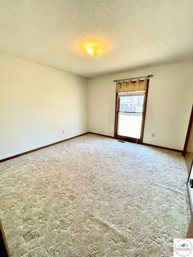 spare room featuring visible vents, carpet flooring, a textured ceiling, and baseboards