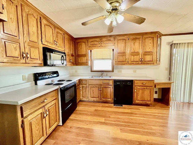 kitchen with brown cabinetry, light countertops, a sink, and black appliances