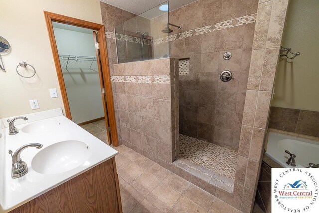 full bathroom with a walk in shower, a spacious closet, a sink, and a garden tub