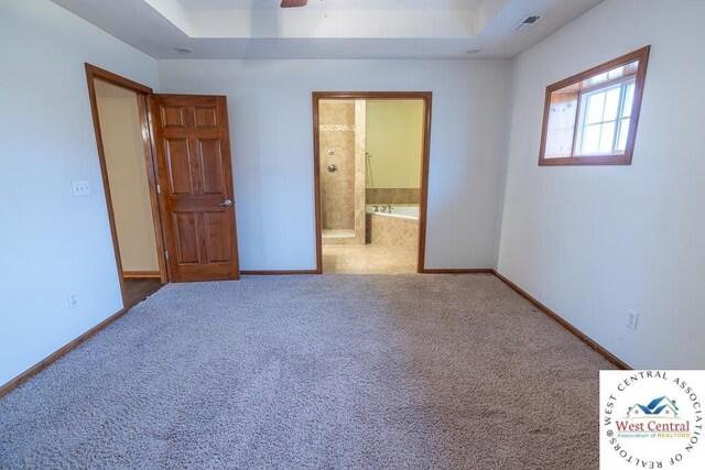 unfurnished bedroom featuring carpet, a tray ceiling, visible vents, and baseboards