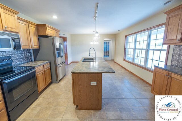 kitchen featuring black range with electric stovetop, backsplash, a kitchen island with sink, a sink, and stainless steel fridge with ice dispenser