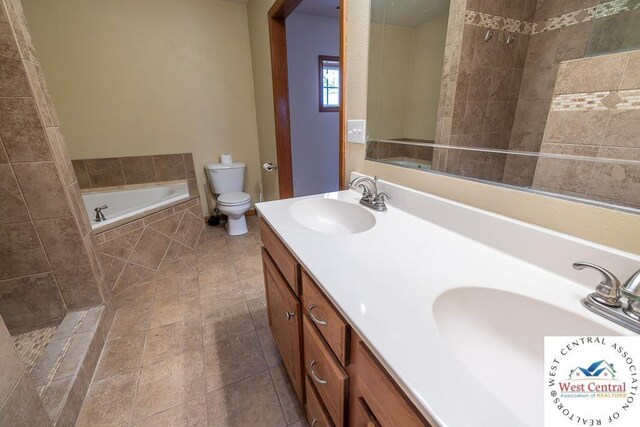 bathroom with tiled bath, a sink, toilet, and double vanity