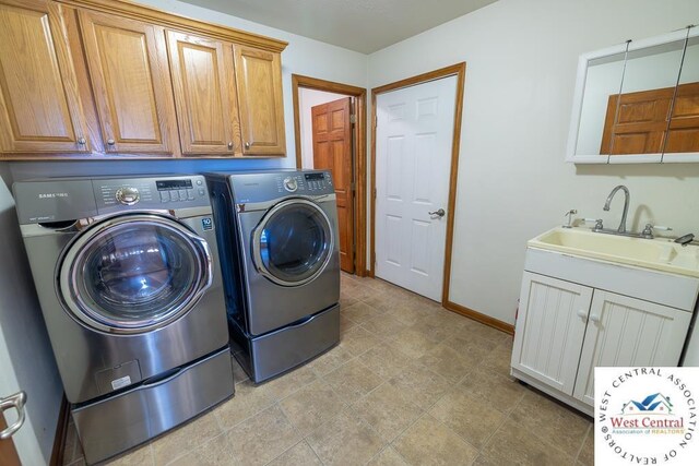 clothes washing area featuring washing machine and clothes dryer, a sink, cabinet space, and baseboards