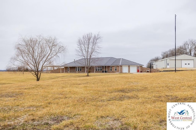 single story home featuring a front yard, metal roof, and an attached garage