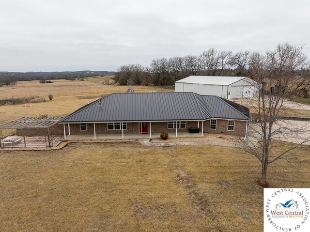 farmhouse featuring brick siding, a patio, a standing seam roof, metal roof, and a front lawn