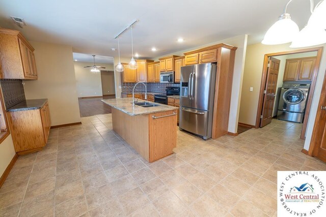 kitchen featuring washer / dryer, visible vents, decorative backsplash, stainless steel appliances, and a sink