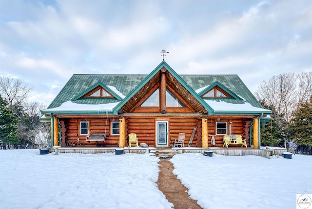 log home with metal roof, log exterior, a porch, and a standing seam roof