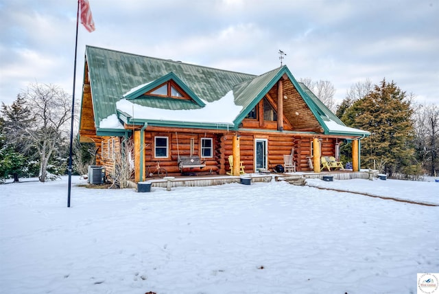 view of front of property with covered porch, log siding, metal roof, and cooling unit