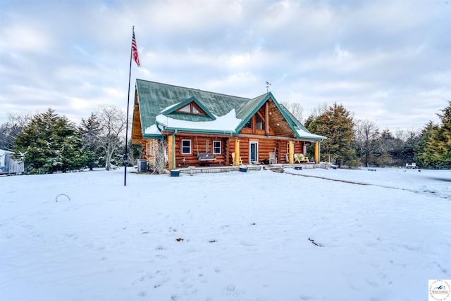 cabin with a porch, log siding, and central AC unit