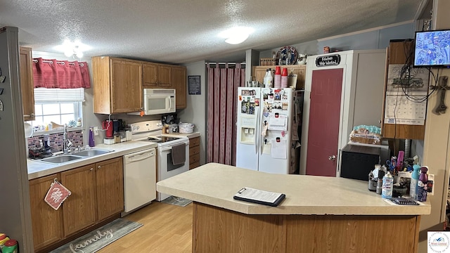 kitchen with a textured ceiling, white appliances, a peninsula, and a sink