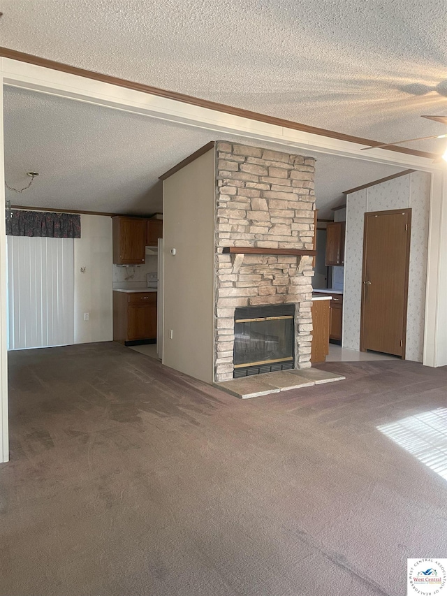 unfurnished living room featuring wallpapered walls, lofted ceiling, a textured ceiling, carpet flooring, and a fireplace