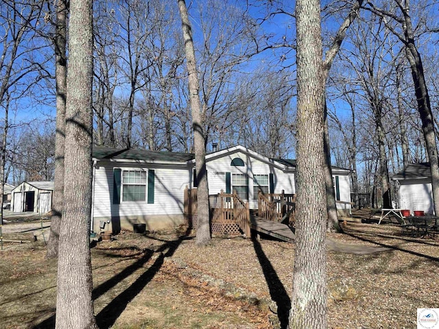 view of front of home featuring a shed, a deck, and an outdoor structure