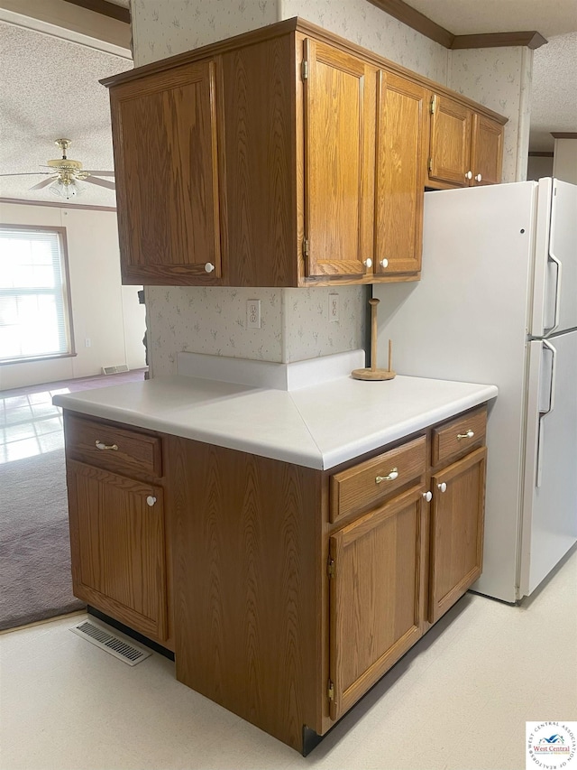 kitchen with a ceiling fan, freestanding refrigerator, visible vents, and wallpapered walls