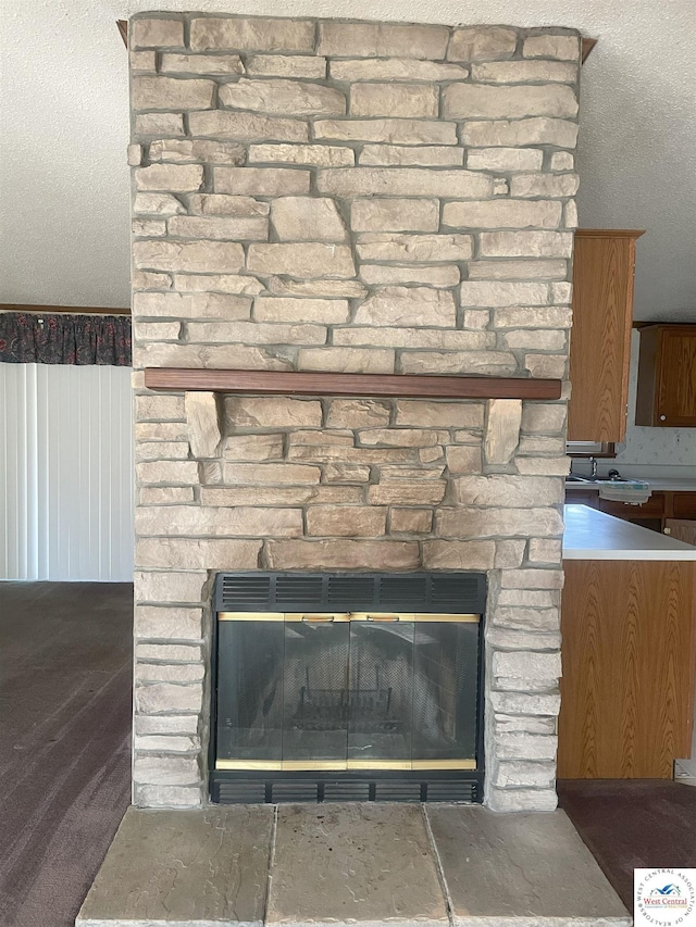 room details featuring a textured ceiling, a sink, and a stone fireplace