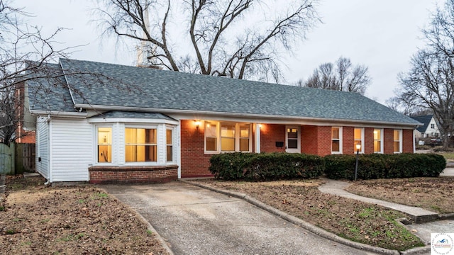 ranch-style home featuring a shingled roof and brick siding