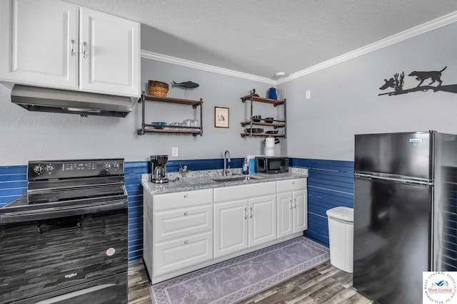 kitchen featuring a wainscoted wall, crown molding, black appliances, a sink, and exhaust hood