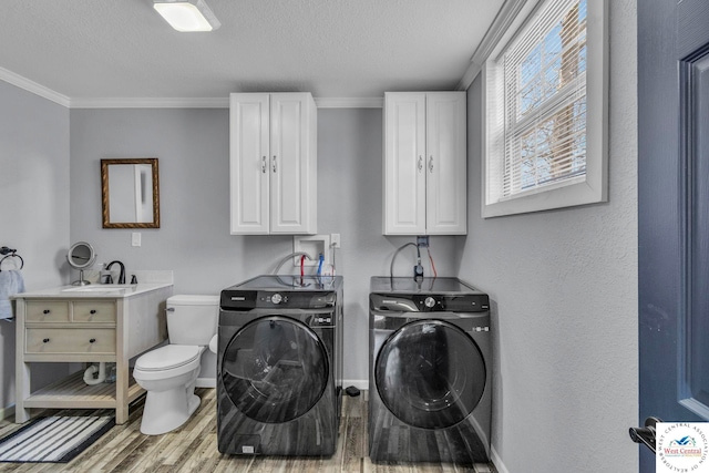 laundry area featuring laundry area, a sink, light wood-type flooring, washing machine and clothes dryer, and crown molding