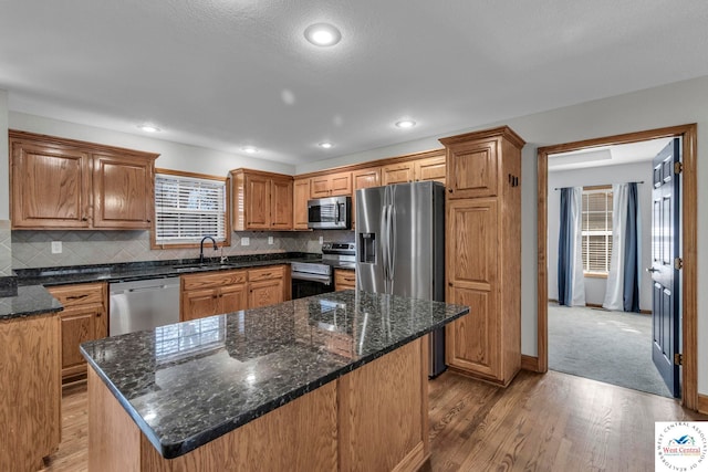 kitchen featuring light wood finished floors, appliances with stainless steel finishes, backsplash, and a sink