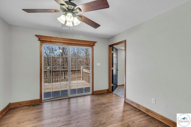 empty room with baseboards, visible vents, ceiling fan, and wood finished floors